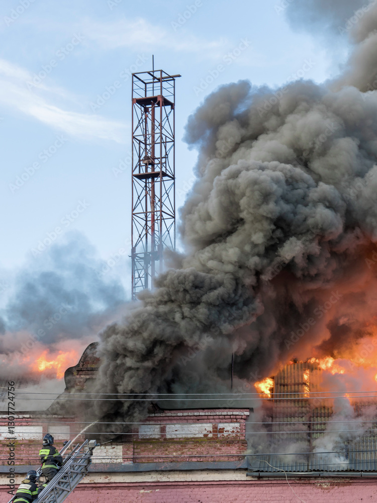Fototapeta premium Fire is burning and a firefighter is spraying water on it
