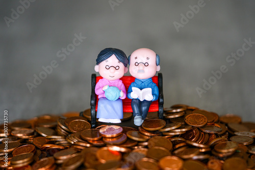 A symbol of financially secure retirement, an elderly couple of doll figurines sitting on coins pile