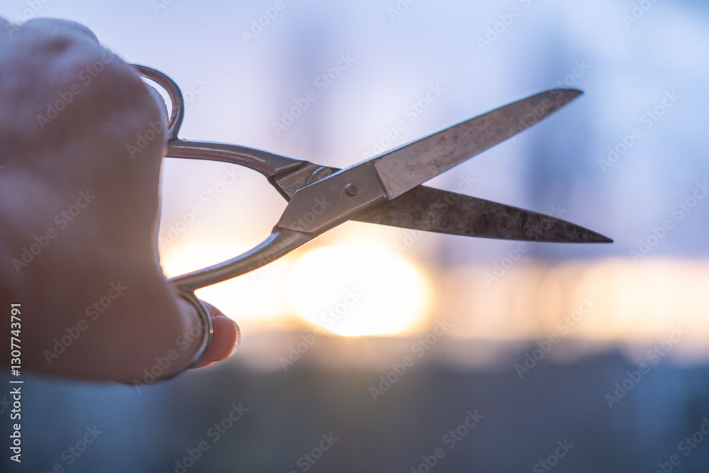 Obraz premium hand holding vintage Rusty old scissors against sunset, symbolizing endings, change, and creativity. Artistic concept, symbolizing decisions, endings, and new beginnings. Conceptual photography