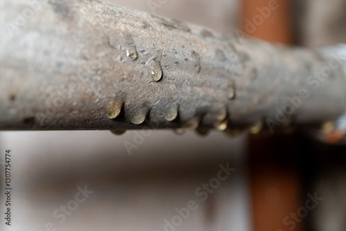 Close-up of water droplets on metal pipe surface indicating moisture and condensation