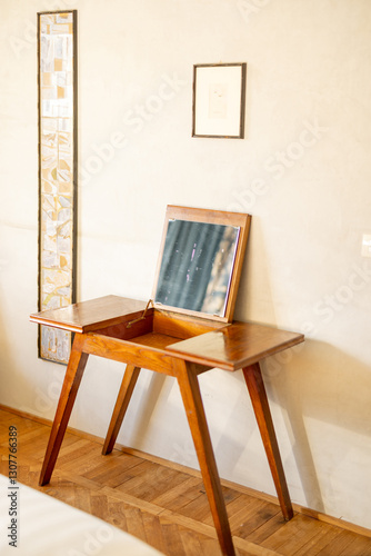 Фотография A beautifully crafted vintage wooden vanity table with a built-in mirror, set against a minimalist wall with framed art