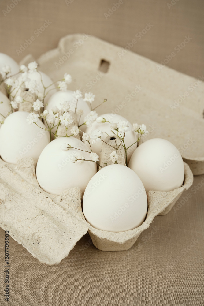 White Eggs with Bbay Wreath Flowers in Open Carton.Natural healthy food and organic farming concept. Eggs in box White Eggs with Bbay Wreath Flowers in Open Carton.Natural healthy food and organic farming concept. Eggs in box