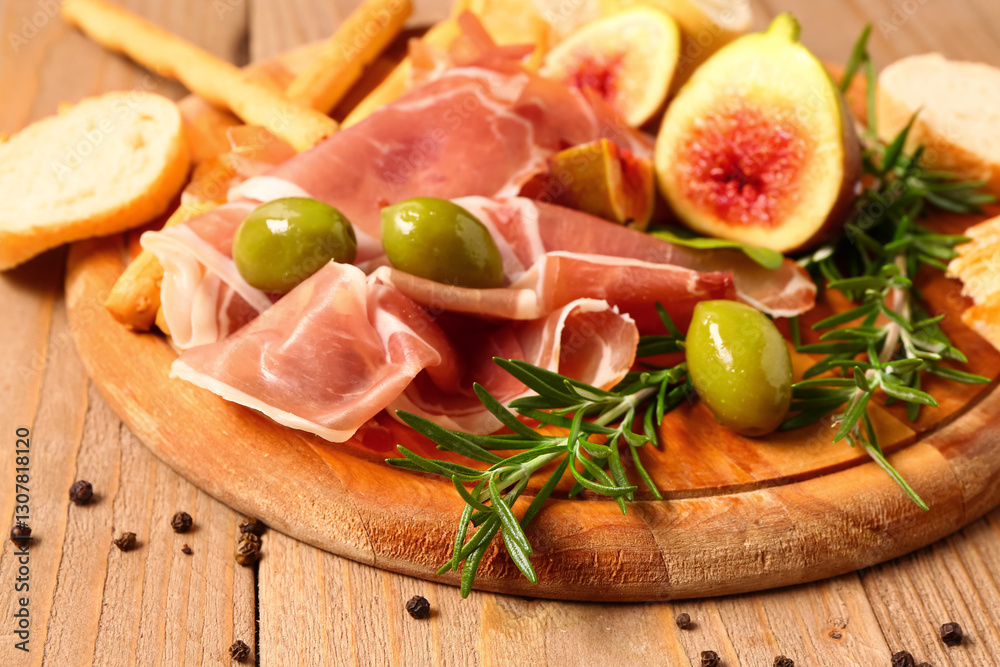 Φωτογραφία Board with slices of tasty prosciutto and olives on wooden background