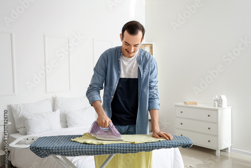 Young man ironing clothes o...
