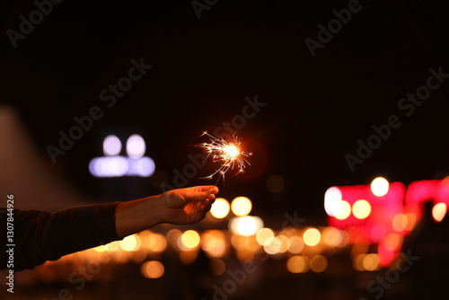 Burning sparkler against bl...