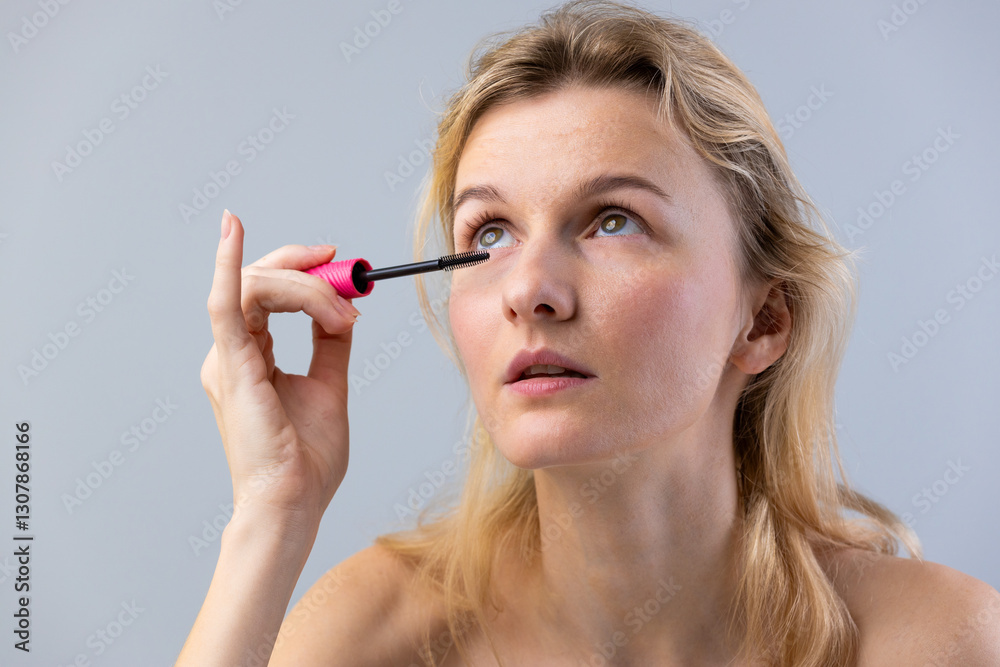 A Young Woman Applying Mascara with a Pink Wand, Focused on Enhancing Her Eyelashes for a Beautiful Look and Capturing the Essence of Modern Makeup Techniques A Young Woman Applying Mascara with a Pink Wand, Focused on Enhancing Her Eyelashes for a Beautiful Look and Capturing the Essence of Modern Makeup Techniques
