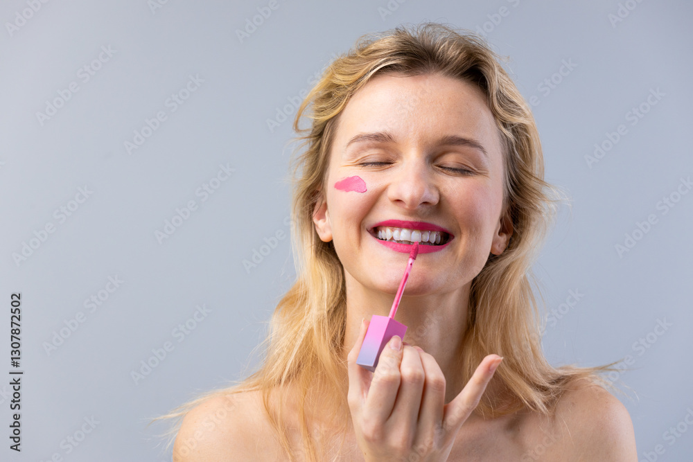Woman applying vibrant pink lipstick with a cheerful smile showcasing the joy of self-expression through beauty and makeup in a light and friendly atmosphere Woman applying vibrant pink lipstick with a cheerful smile showcasing the joy of self-expression through beauty and makeup in a light and friendly atmosphere