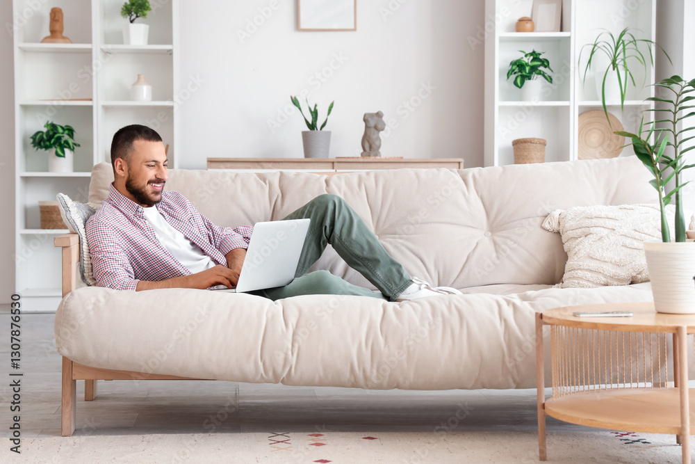 Freelancer lying on sofa and using laptop at home Freelancer lying on sofa and using laptop at home