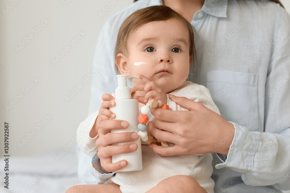 Little baby with cream on her cheek sitting on mum's lap in bedroom. Closeup Little baby with cream on her cheek sitting on mum's lap in bedroom. Closeup