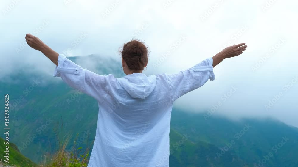 Rising hands by mountains with fog. A happy lady traveler stand with rising hands against green mountains in fog in Europe. Rising hands by mountains with fog. A happy lady traveler stand with rising hands against green mountains in fog in Europe.