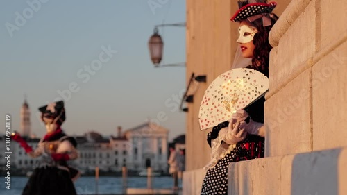 Venice, Italy - People dressed in carnival masks are photographed by tourists in the scenery of the ancient Venetian palaces