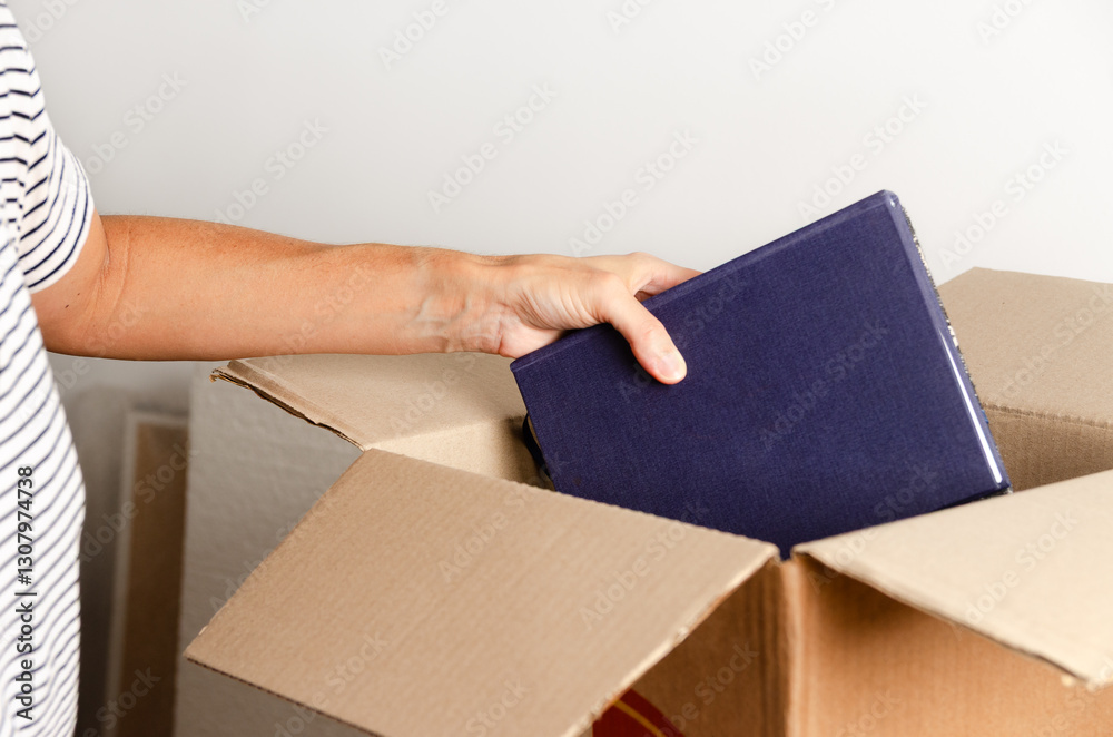 © Cecilia Di Dio - A woman's hand putting books into a cardboard box. © Cecilia Di Dio - A woman's hand putting books into a cardboard box.