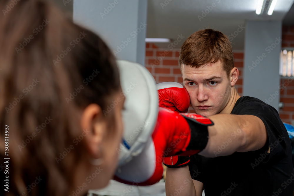 Young boxer training, punching focus mitt held by coach Young boxer training, punching focus mitt held by coach