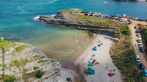 A secluded Black Sea beach, turquoise waters meeting rocky shores, people swimming and camping, blending untouched natural beauty with peaceful holiday vibes. Sardalya Bay, Kandıra, Kocaeli, Turkey 
