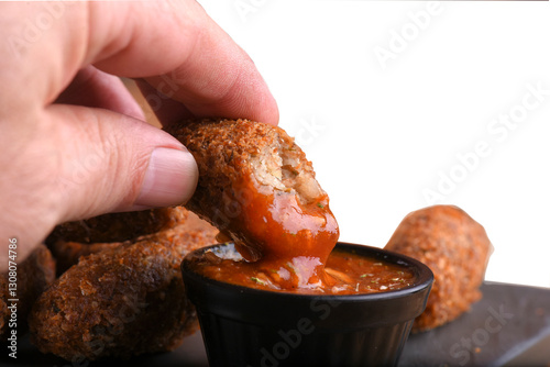 delicious fried cod dumpling with herb sauce on the table in the dark background with blurred mug of draft beer.