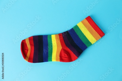 One sock in LGBT colors on light blue background, top view