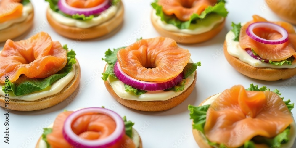 Miniature bagels topped with smoked salmon, creamy spread, red onion rings, and fresh lettuce, arranged in a visually appealing pattern for a delicious and appetizing food photography image. Miniature bagels topped with smoked salmon, creamy spread, red onion rings, and fresh lettuce, arranged in a visually appealing pattern for a delicious and appetizing food photography image.