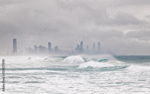 Heavy surf with breaking waves with wind spray and threatening skies with Surfers Paradise in the background as the edge of cyclone Alfred touches on the Gold Coast in Queensland, Australia.
