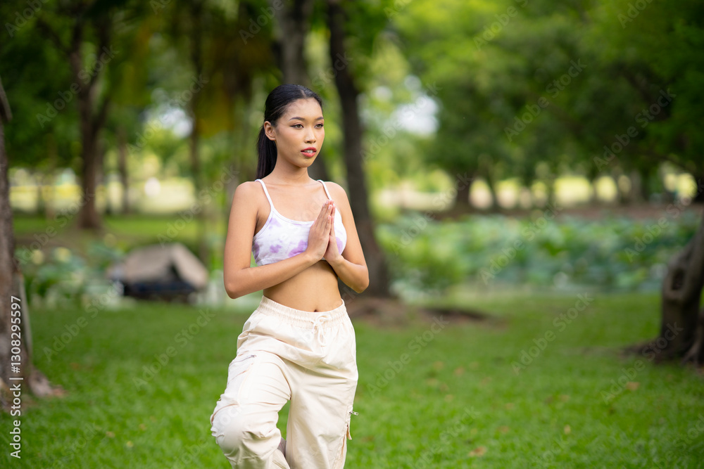 Fit sporty mindful young Asian woman meditating doing yoga breathing exercises feeling peace of mind, mental balance standing in green nature tropical park on sunny day. Fit sporty mindful young Asian woman meditating doing yoga breathing exercises feeling peace of mind, mental balance standing in green nature tropical park on sunny day.