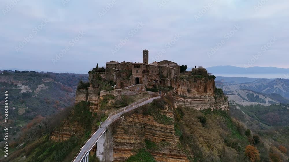 Aerial view capturing the ancient Etruscan city of Civita di Bagnoregio, perched on a volcanic tuff plateau and accessible by bridge Aerial view capturing the ancient Etruscan city of Civita di Bagnoregio, perched on a volcanic tuff plateau and accessible by bridge