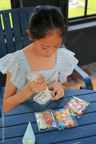 Obraz na płótnie Asian girl child enjoy baking cake, decorating DIY cupcake. w salonie
