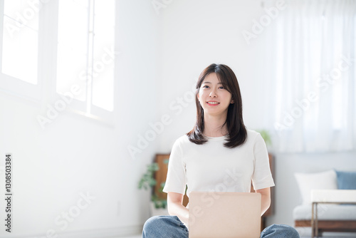 Принти на полотні Young woman in casual clothes in the living room, sitting on the computer on her