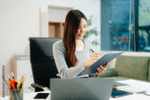 Free Download Young attractive Asian woman smiling thinking planning writing in notebook, tablet and laptop working from home - GFXLoad