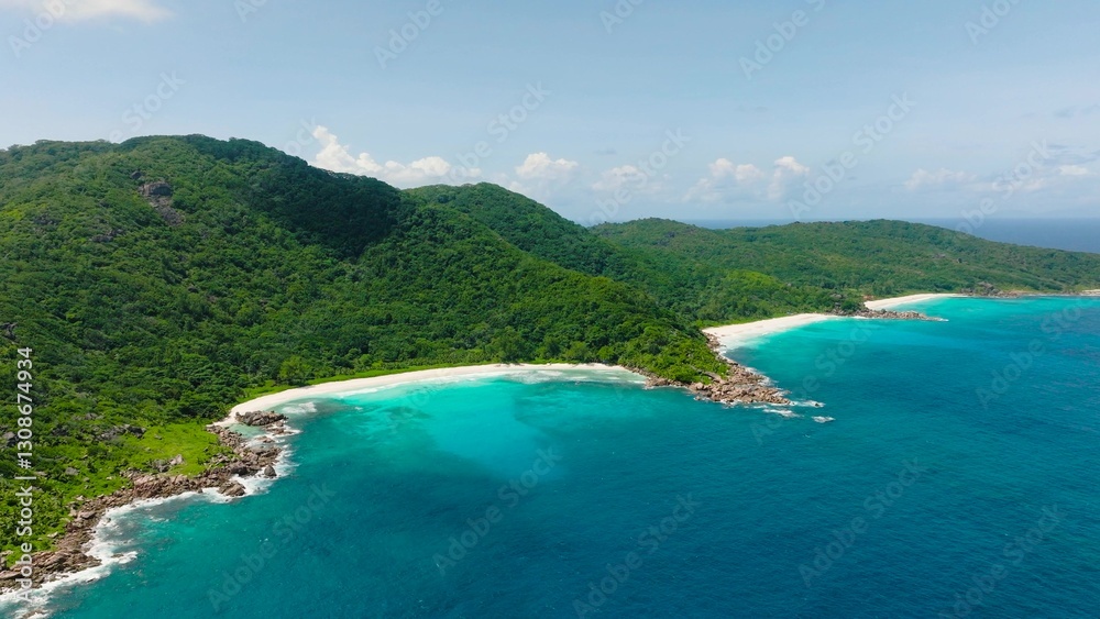 Aerial view of a peaceful turquoise beach surrounded by lush green hills. La Digue, Seychelles. Aerial view of a peaceful turquoise beach surrounded by lush green hills. La Digue, Seychelles.