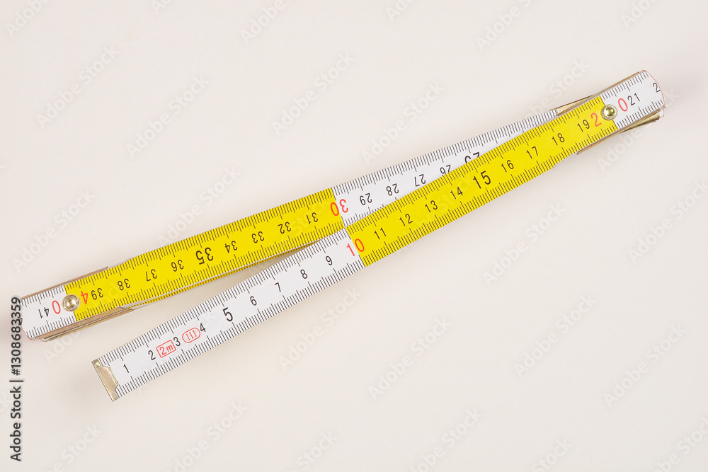 A slightly angled, top-down shot of a partially unfolded wooden folding ruler against a light background