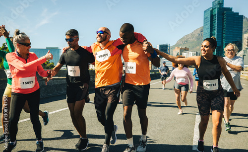 Fotografie Teammates help injured runner during city marathon race