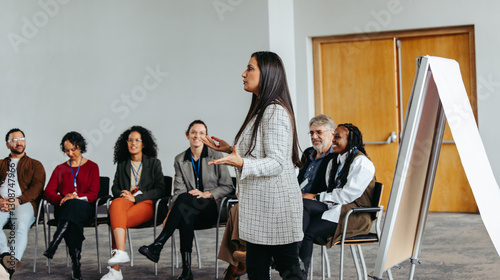 Female instructor leading teambuilding session with diverse group in modern office setting