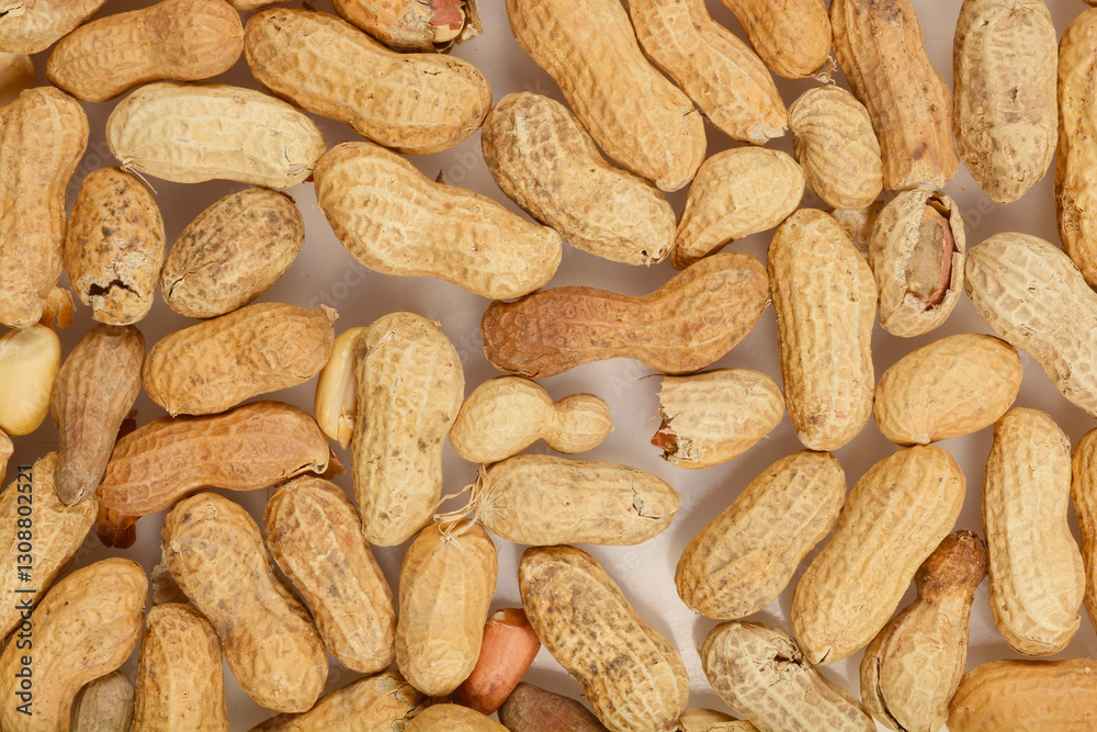 A close-up, top-down view of a scattered pile of raw peanuts in their shells, displaying a variety of textures and natural colors A close-up, top-down view of a scattered pile of raw peanuts in their shells, displaying a variety of textures and natural colors