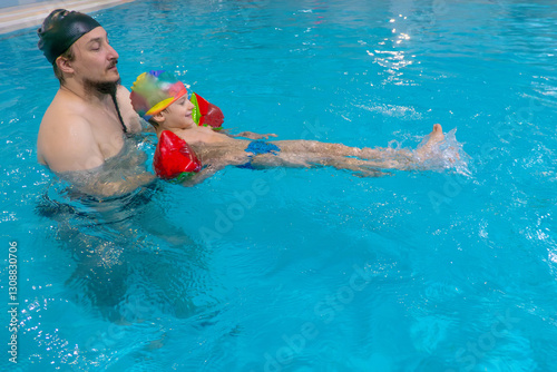 Happy middle-aged father swimming with cute adorable baby in swimming pool. Smiling dad and little child, boy having fun together. Active family spending leisure and time in spa hotel. Concept of kids