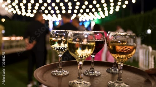 Close up view of the waiter serving glasses of white and red wine to the guests with a tray at a party. Catering or celebration concept.