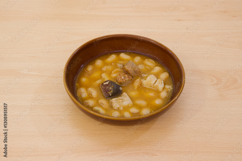 A bowl of soup with beans and meat in it