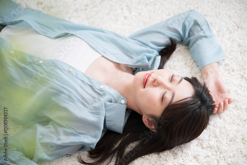 Billede på lærred Overhead close-up of a relaxed young woman lying on her back in a room, eyes clo