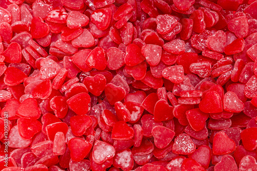 Textured surface of red heart gummy candies covered in sugar and starch from the candy factory production