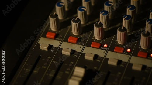 Audio console with moving faders and colored meters.