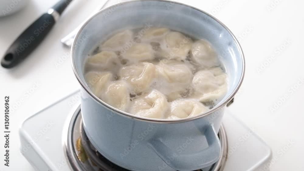 young man cooking dumplings in the kitchen, putting them to the boiling water young man cooking dumplings in the kitchen, putting them to the boiling water