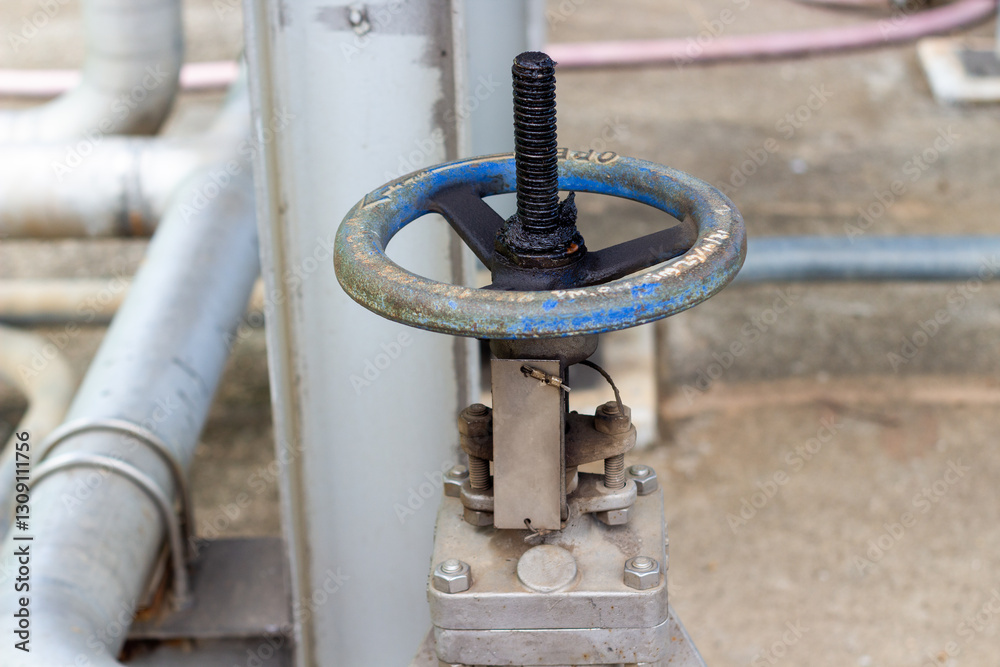 Industrial water valve with a worn blue wheel. Pipes and industrial setting Industrial water valve with a worn blue wheel. Pipes and industrial setting