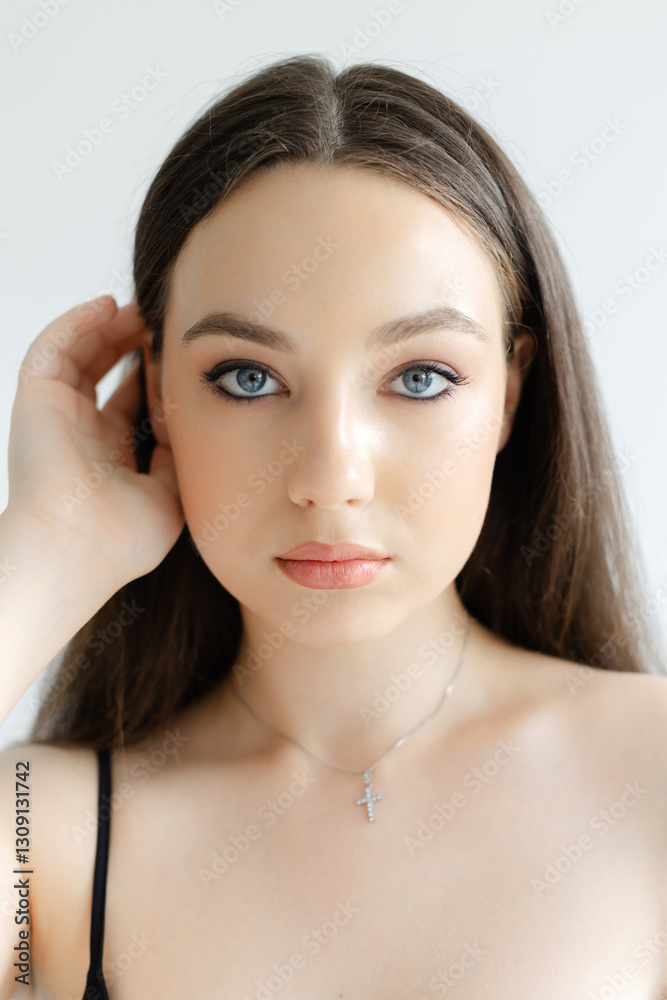 Naklejka premium Young woman touching her hair wearing a necklace with a cross pendant