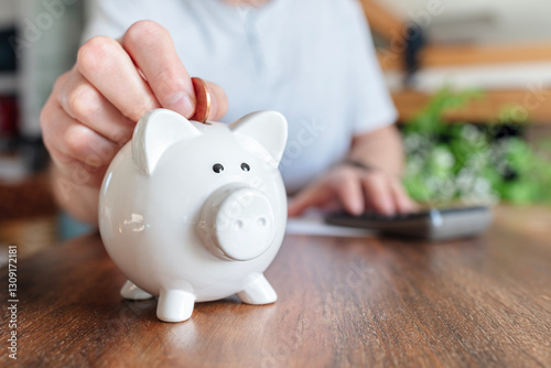 Piggy bank savings, man putting a coin into a pink piggybank