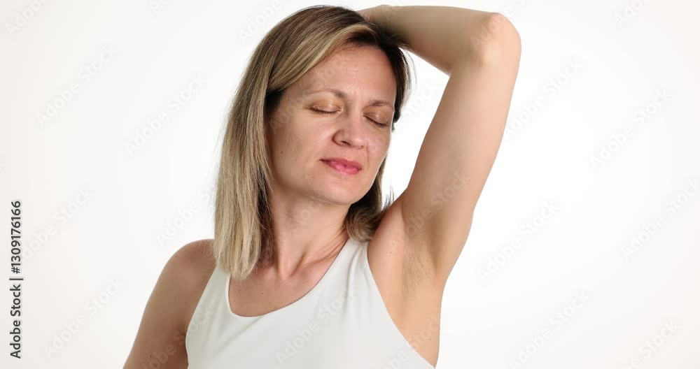 A woman thoughtfully examines her underarm for freshness and cleanliness in a bright, open, airy setting A woman thoughtfully examines her underarm for freshness and cleanliness in a bright, open, airy setting