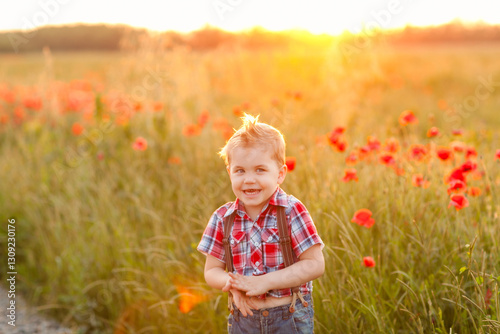 A playful little boy with strabismus in front of a poppy field at sunset, smiling and laughing
