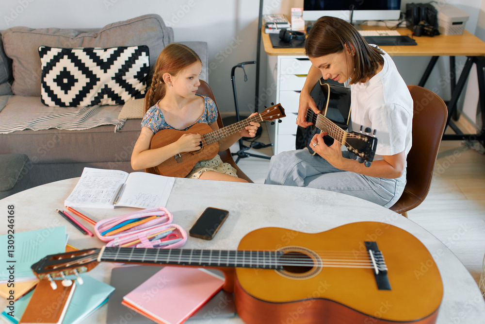 Fototapeta premium Mother and daughter play musical instruments together in living room setting during afternoon