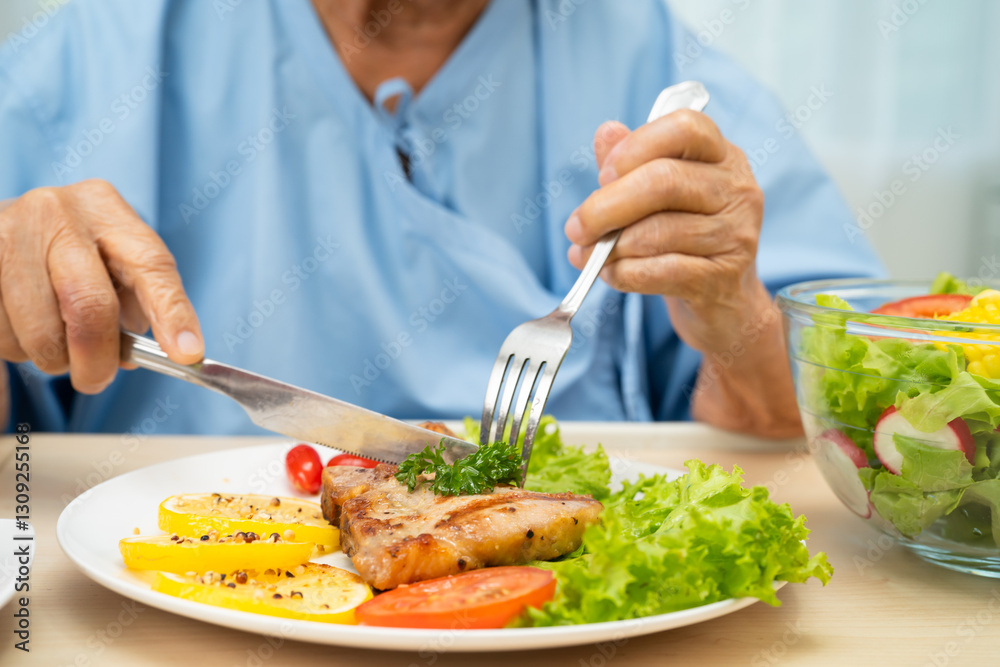 Asian senior woman patient eating pork chop stake and vegetable salad for healthy food in hospital. Asian senior woman patient eating pork chop stake and vegetable salad for healthy food in hospital.