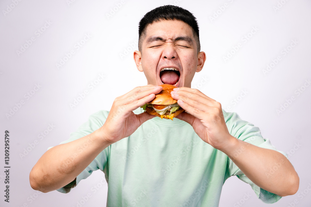 A close-up shot of an Asian man holding a cheeseburger with both hands, ready to take a big bite. The burger has lettuce, tomato, cheese, and a beef patty. The background is white A close-up shot of an Asian man holding a cheeseburger with both hands, ready to take a big bite. The burger has lettuce, tomato, cheese, and a beef patty. The background is white
