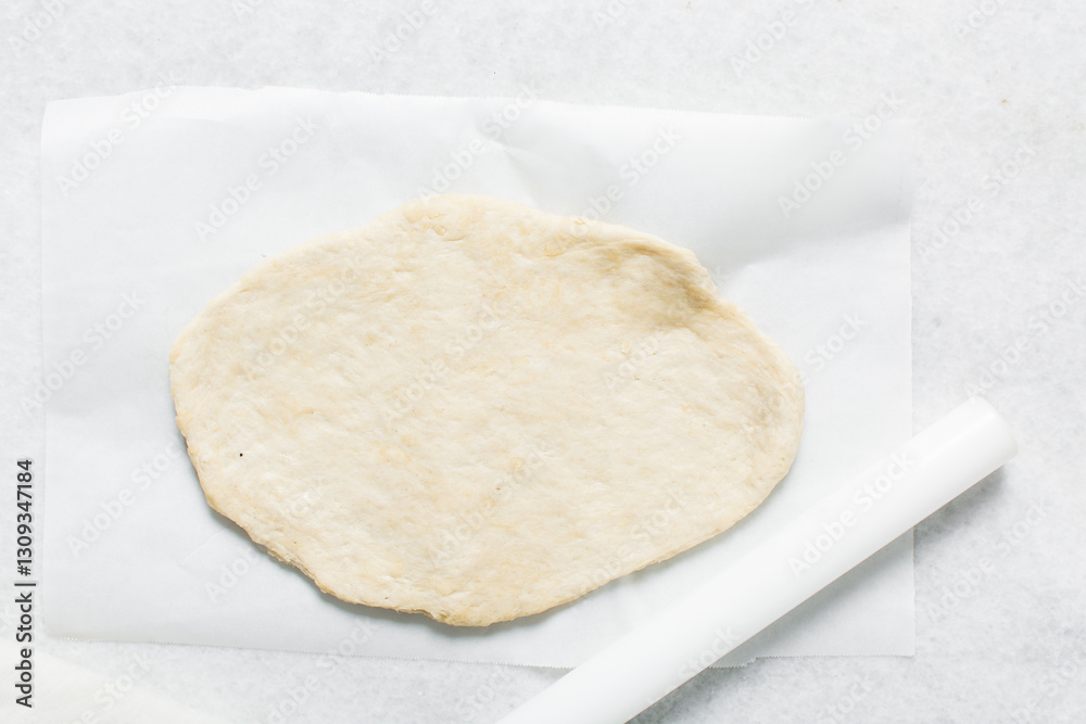 Overhead view of crackers dough on parchment paper, cracker biscuit dough on white background, process of making crackers Overhead view of crackers dough on parchment paper, cracker biscuit dough on white background, process of making crackers