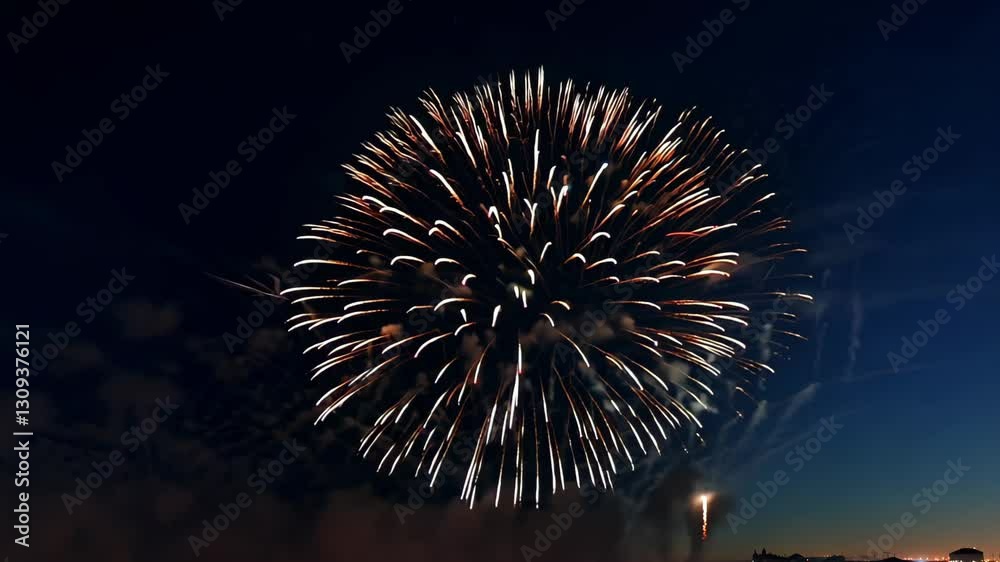 Spectacular red fireworks explosion lights up the dark night sky. The glowing sparks and smoke