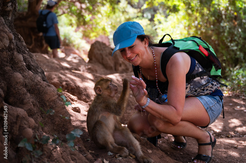 Canvas Print The tourist is having fun with macaque monkey near the Ouzoud waterfall,